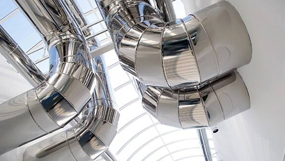 Stainless steel HVAC ductwork and ventilation pipes in a modern commercial building.